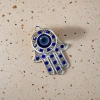 A fashionable and individual necklace with a silver hand-shaped pendant set with blue gemstones and blue eye ornaments details Picture